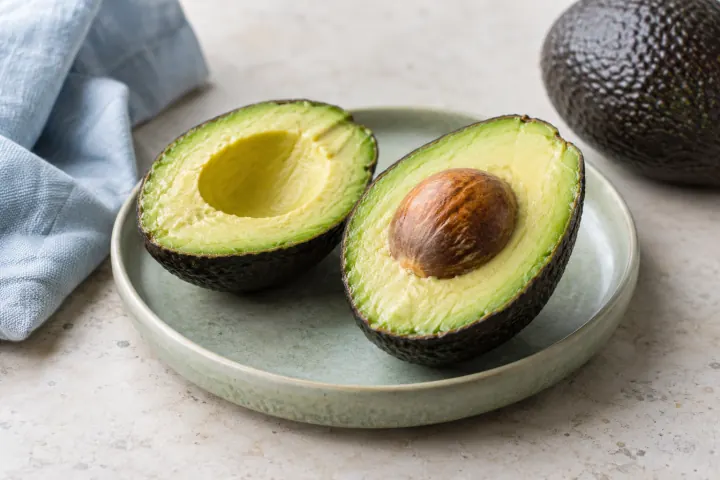 Avocado halves on a pale ceramic plate